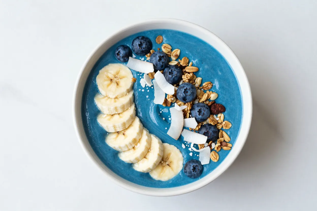 Ocean blue smoothie bowl made with blue spirulina extract topped with banana, blueberries, coconut and granola